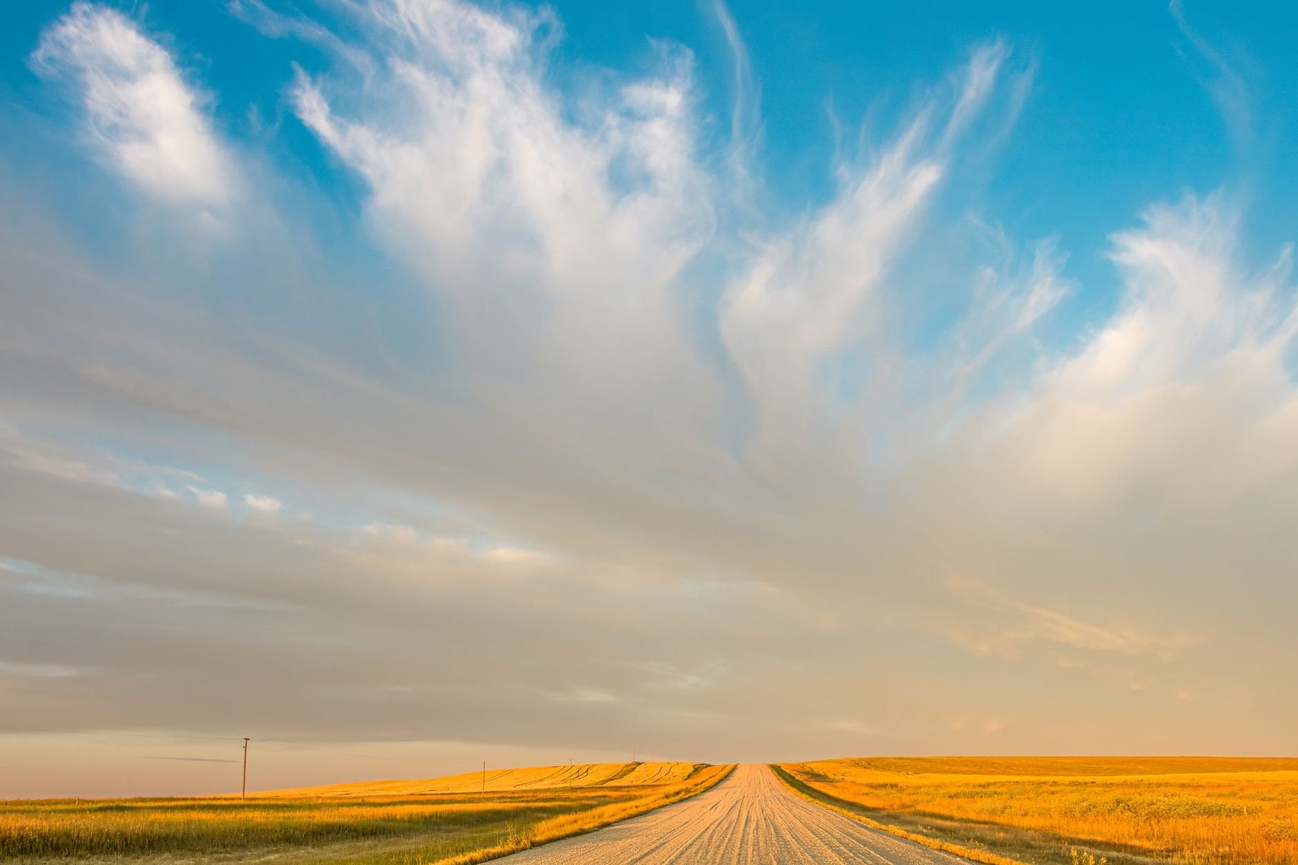 A rural prairie road under a big evening sky